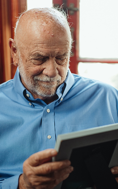 elderly man looking at a photo of his loved ones