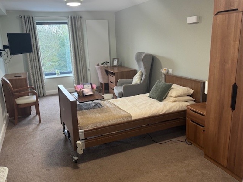 bedroom with a profiling bed, 2 armchairs, a television and storage