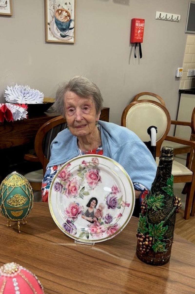 resident holding up their arts and crafts pieces ready for an exhibition