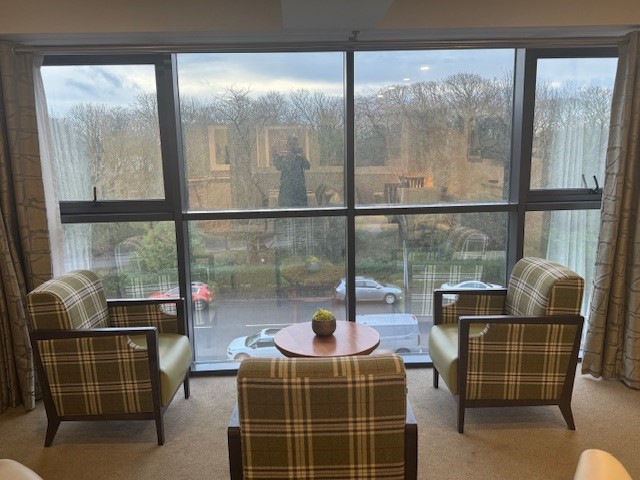 3 armchairs around a table next to a window