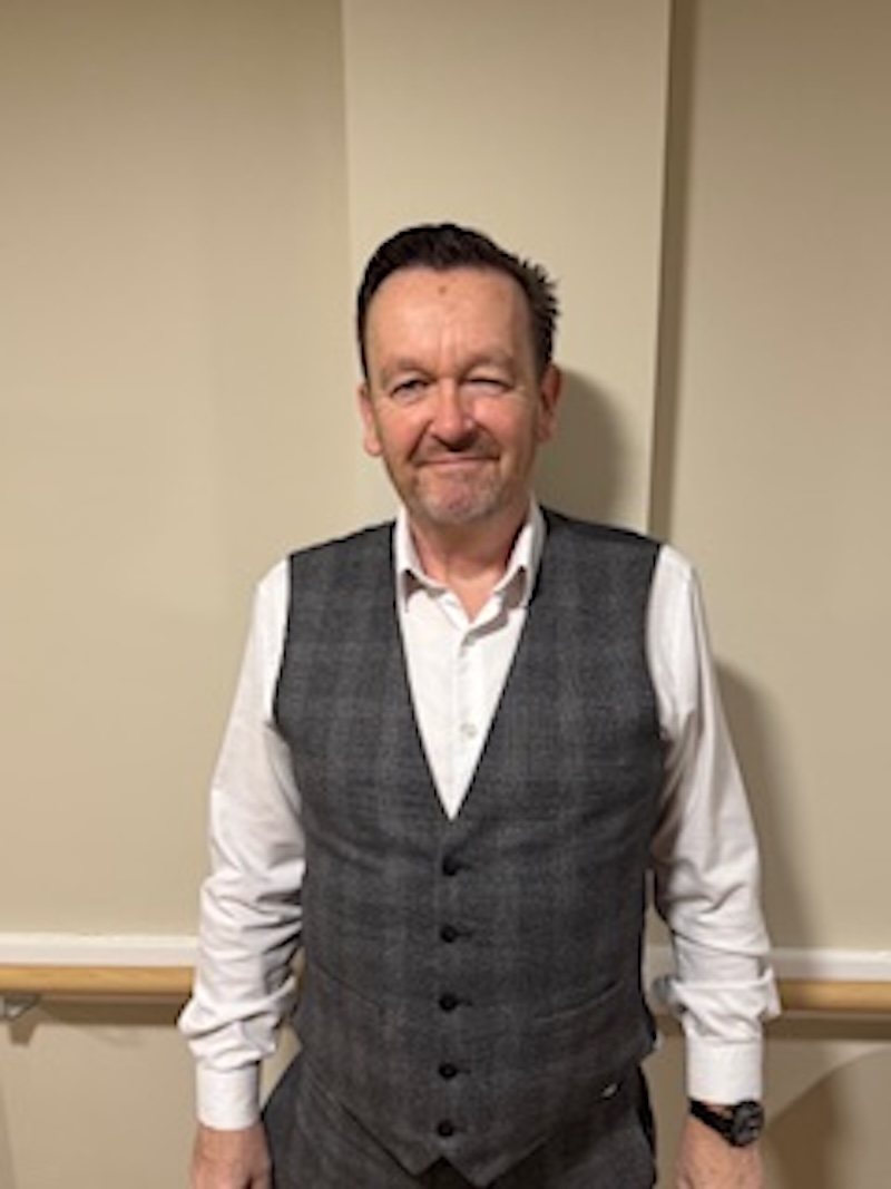Man with brown hair wearing a suit having his headshot taken for the team page