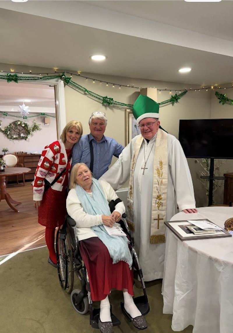 group photo of resident and their loved ones with father patrick