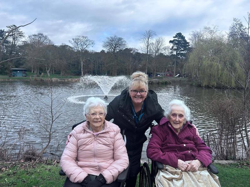 2 residents out in the community in front of a pond with a fountain