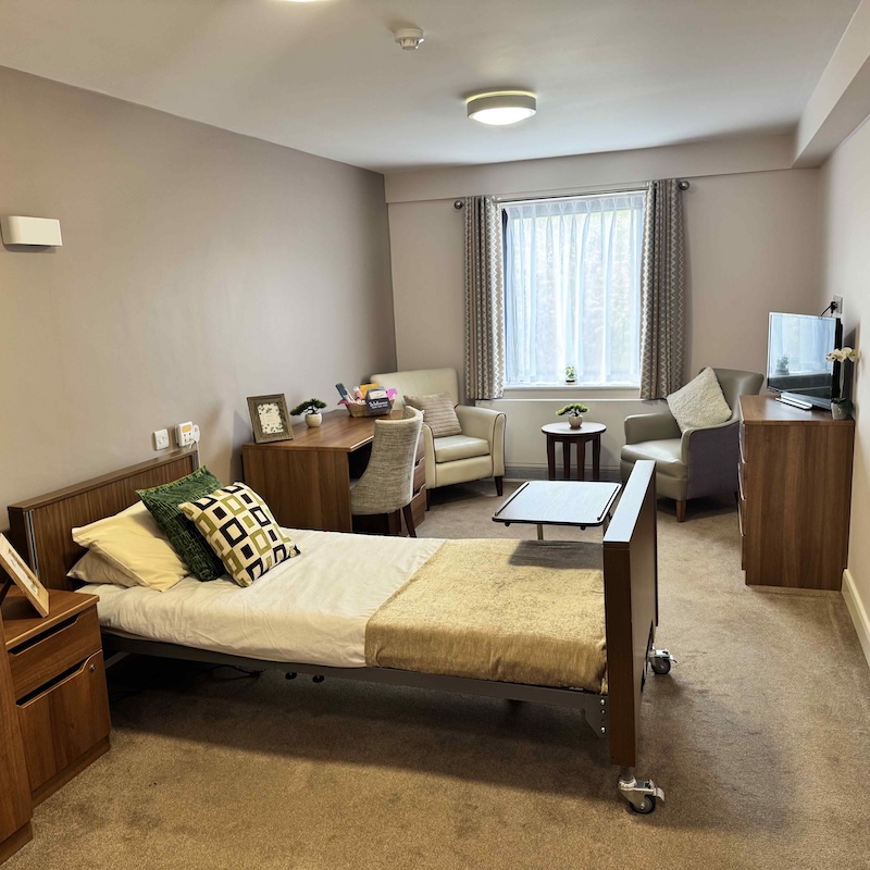 bedroom at hesketh park lodge with a bed, armchairs, desk and storage
