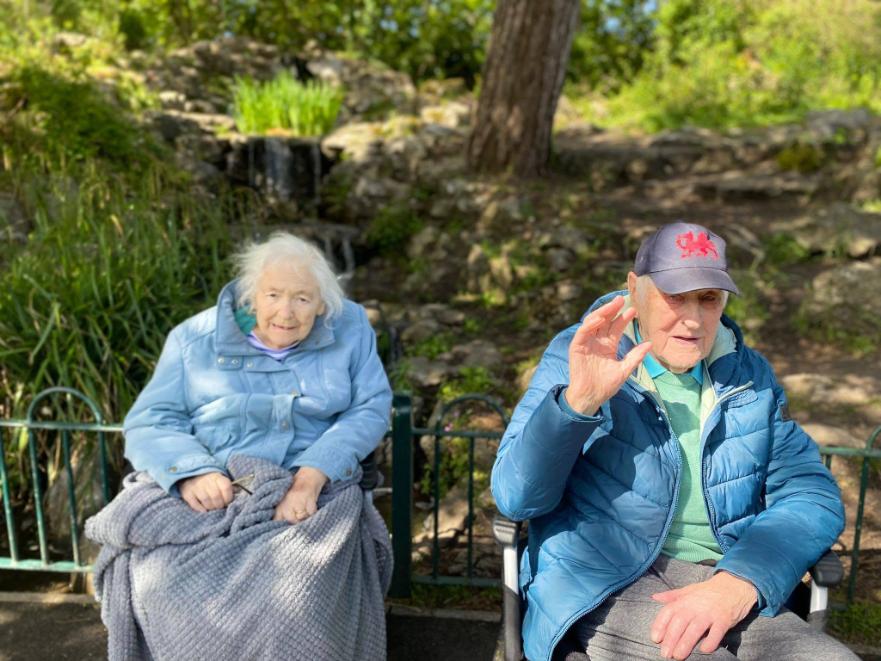 2 residents sat down in their wheelchairs smiling while on an outing