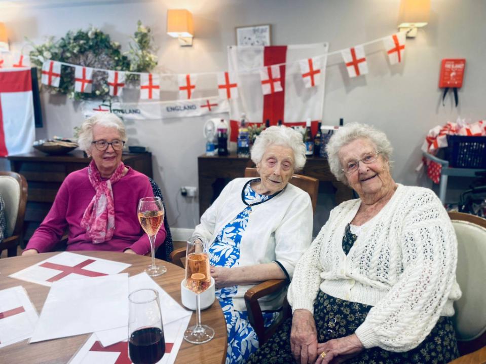 three older ladies sat at a table with english flags behind them