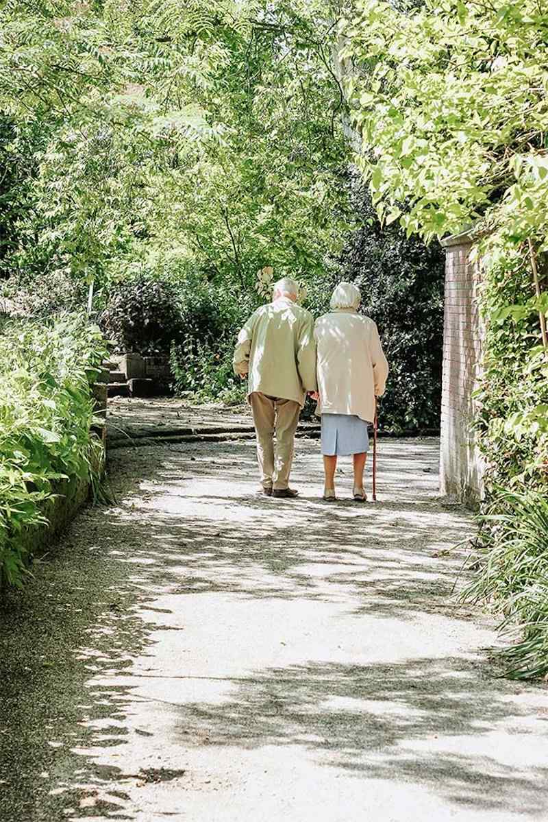2 residents walking down a woodlands path holding each other