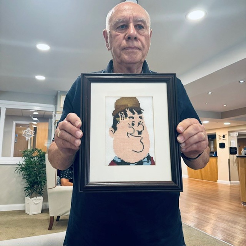 man holding a cross stitching artwork