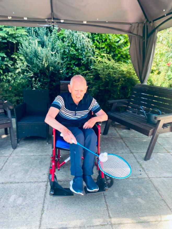 older man in a wheelchair holding a badminton racket
